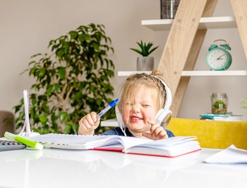 Ein Kind mit Kopfhörern auf dem Kopf, das am Schreibtisch sitzt