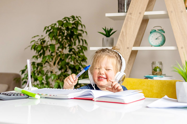 Ein Kind mit Kopfhörern auf dem Kopf, das am Schreibtisch sitzt